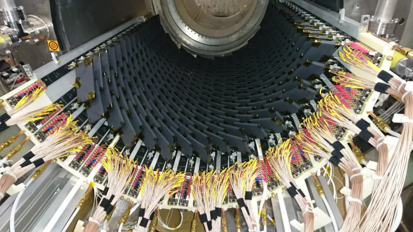 Lさんがメンテナンス・運用・較正（こうせい）を担当している検出器（陽電子タイミングカウンター）。「電子の反物質である陽電子を40ピコ秒！（1秒の1万分の1の1万分の1の1万分の1が1ピコ秒）の精度で測定します」<br />Copyright © 2024,  K. Afanaciev et al